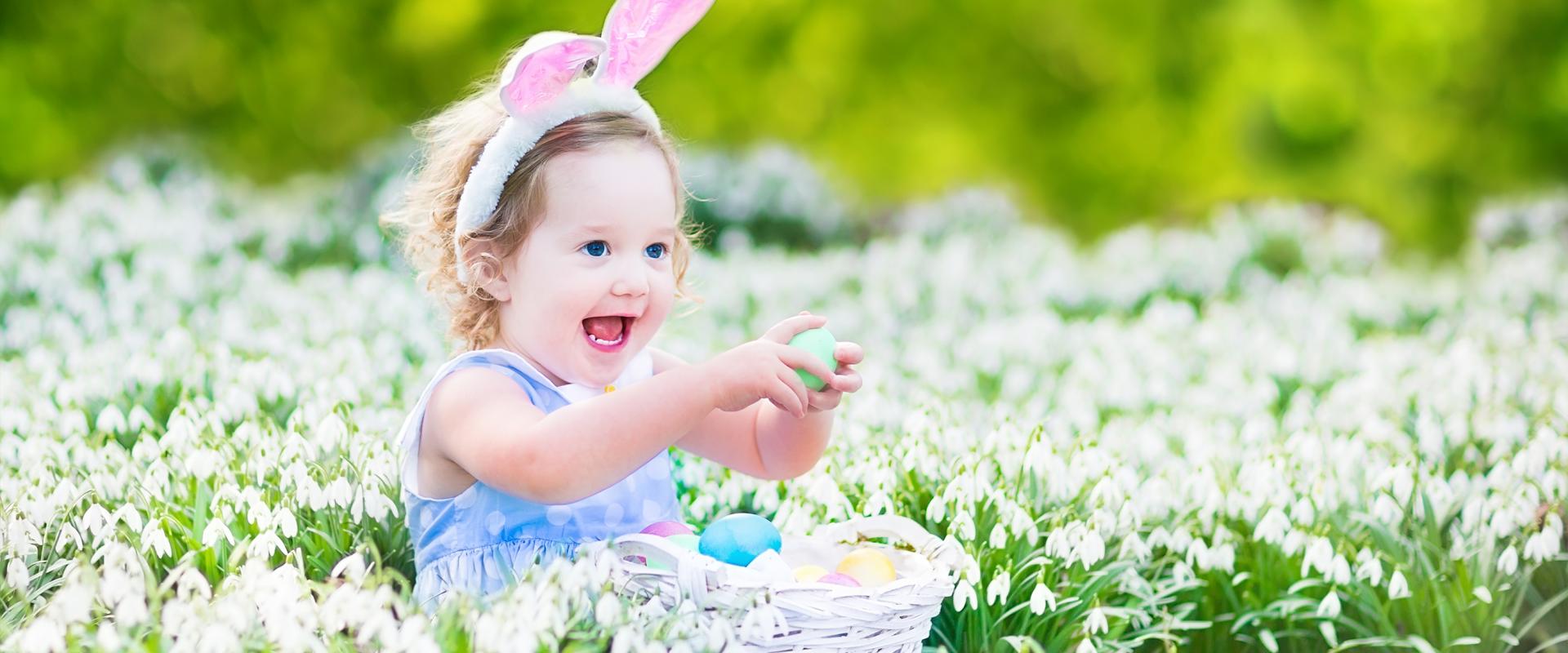 merch ifanc yn eistedd mewn dôl, gydag wyau Pasg a chlustiau bwni / young girl sitting in a meadow, with Easter eggs and bunny ears