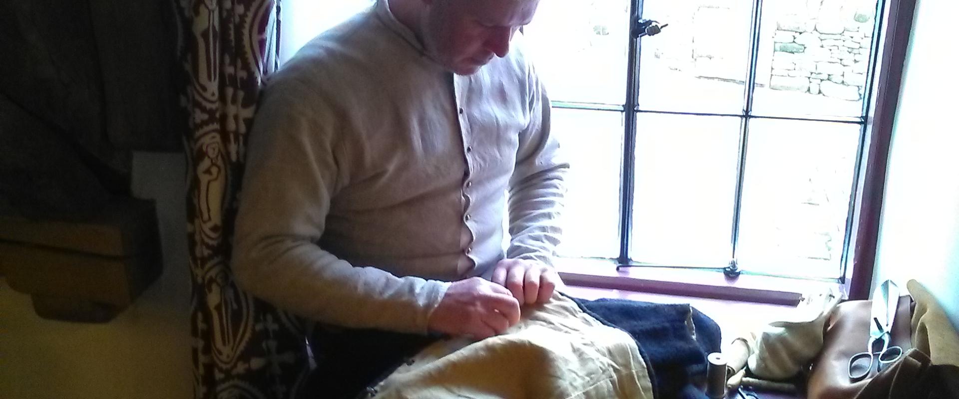 A Tudor tailor sitting on a window ledge