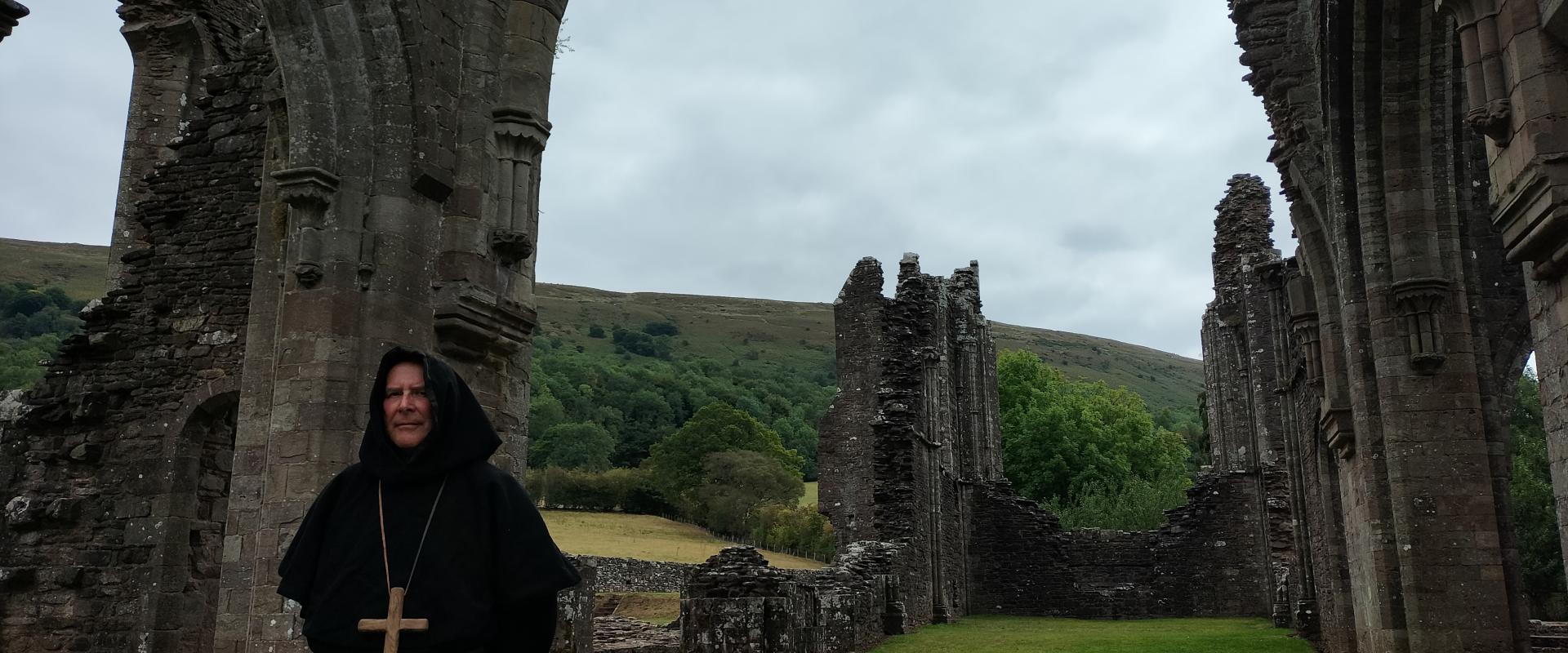 Monk in a black habit in the ruins of the priory