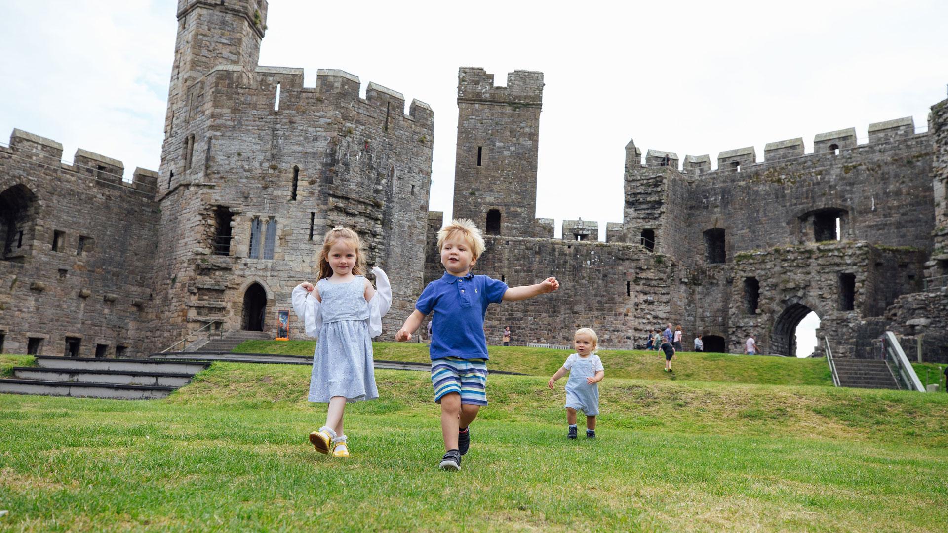 Castell Caernarfon / Caernarfon Castle interior - children running across grass