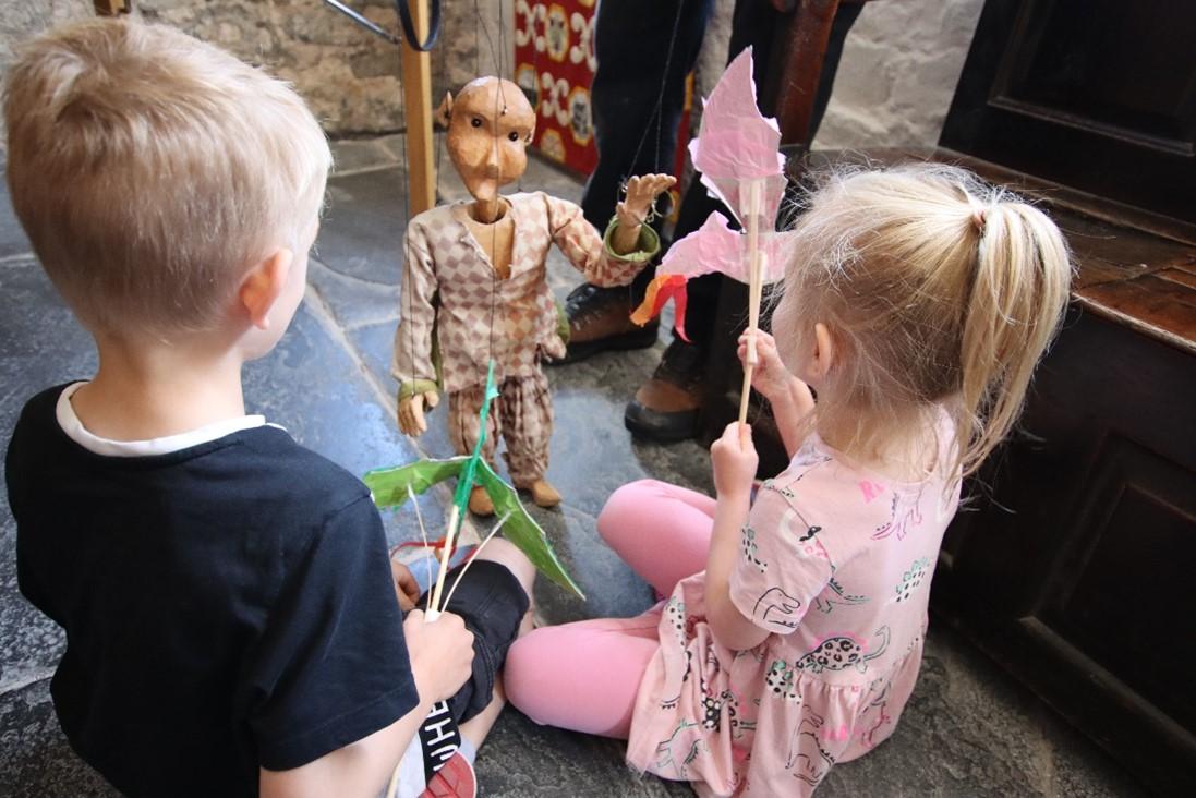 A young boy and girl watch a puppet demonstration